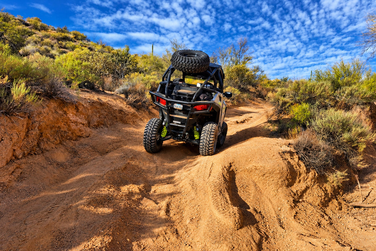 Rear view of Polaris RZR Trail 900 Sport with PERFEX lift kit tackling sandy off-road trail.