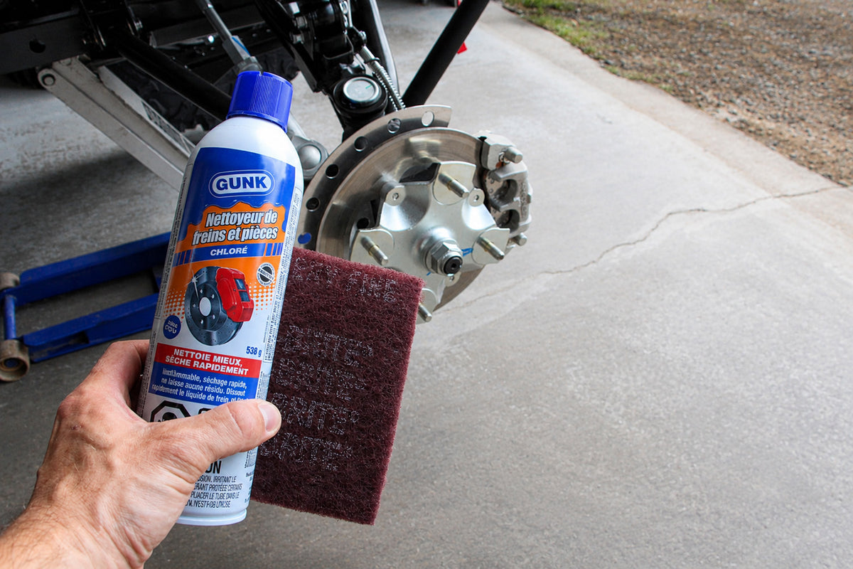 Cleaning the ATV or UTV wheel hub with brake cleaner and an emery pad to ensure the wheel spacer sits perfectly flush.