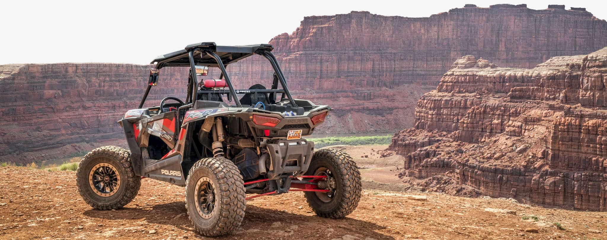 Polaris RZR 1000 XP featured on the Satisfaction Guarantee page of the Perfex website. The UTV is seen atop a mountain.