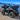 Blue CFMOTO CForce 500 HO with a PERFEX suspension lift, featuring a raised stance and rugged all-terrain tires on a rocky lakeshore.