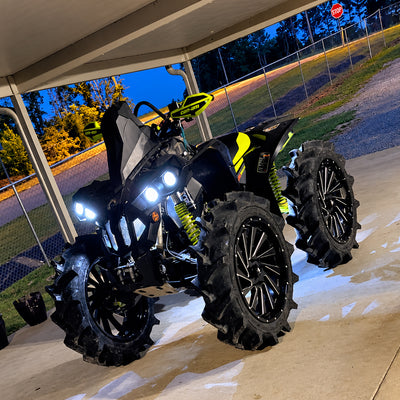 Can-Am Renegade 1000R ATV with PERFEX 2" lift kit shown from the front at dusk with headlights on and aggressive mud tires.