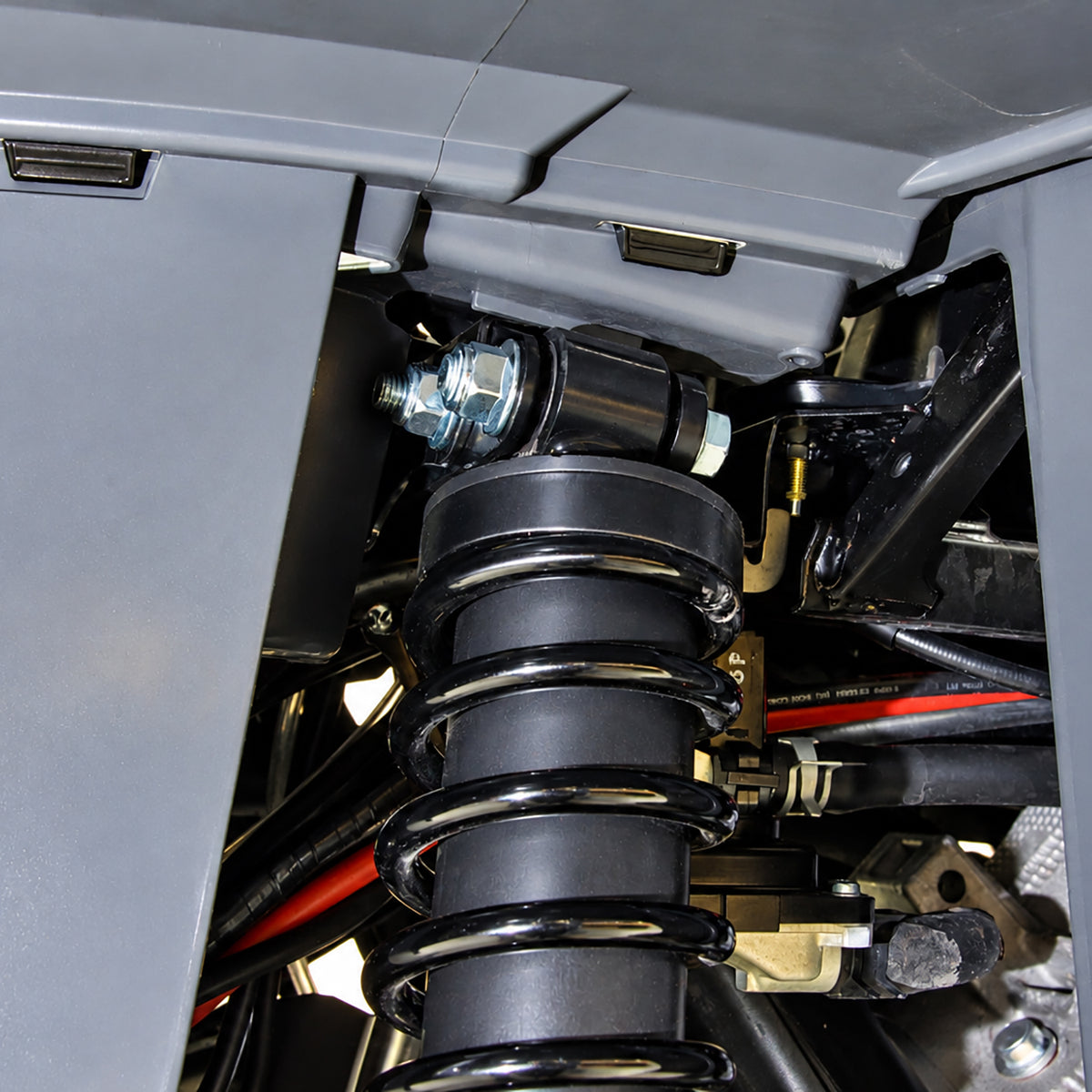Close-up of the front lift brackets and spring spacer installed on a Yamaha Kodiak 450 ATV suspension as part of the PERFEX 2-inch lift kit.