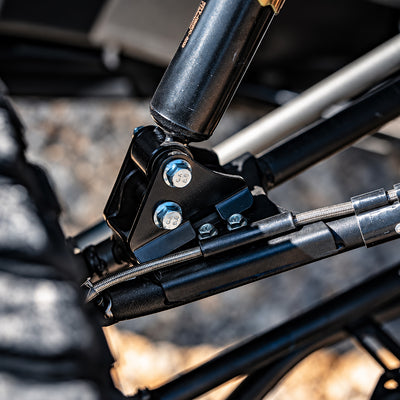 Detailed view of a PERFEX front suspension lift brackets mounted to the lower shock absorber on a CFMOTO UForce 1000 UTV.