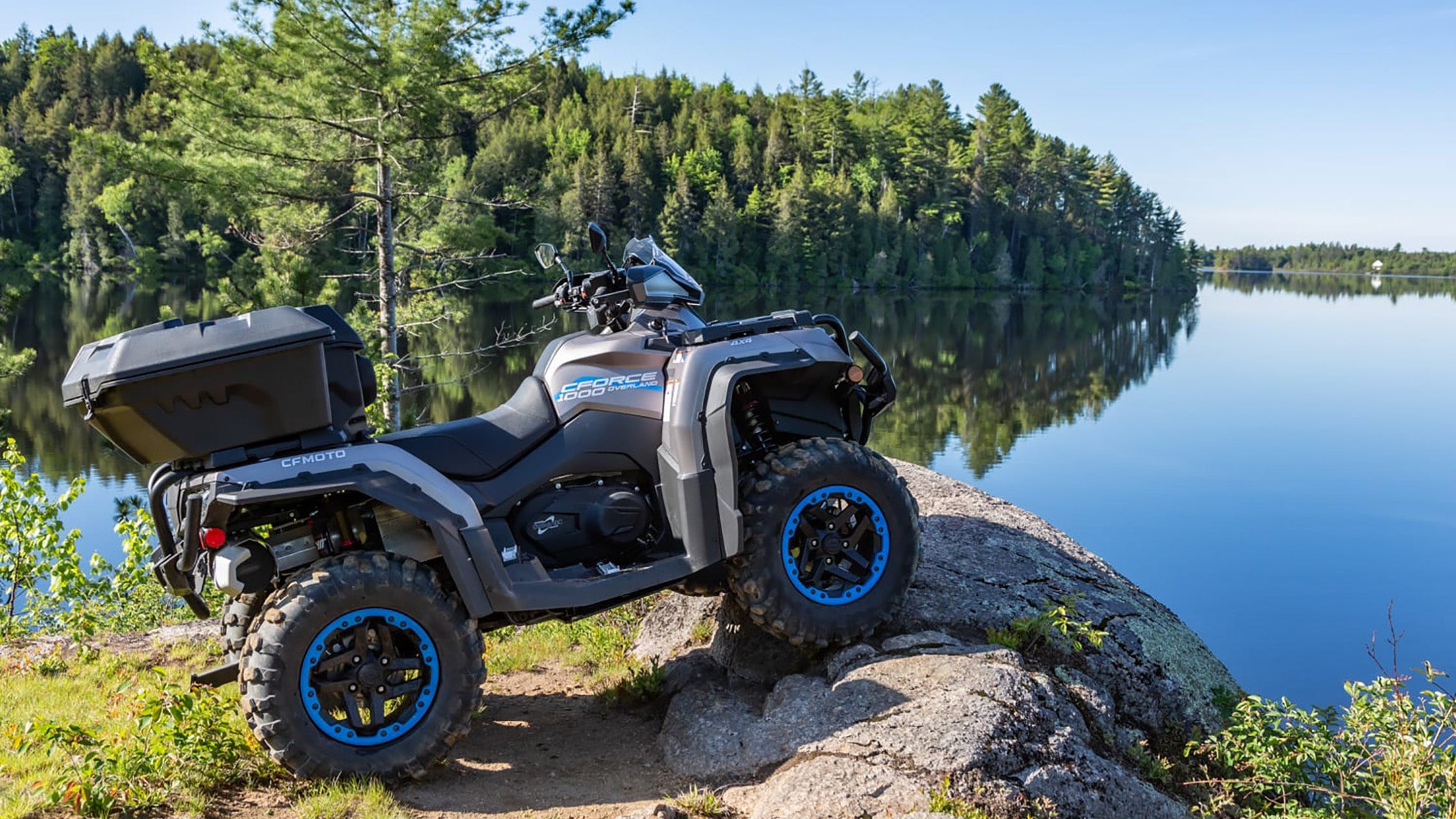CFMoto CForce Overland (ATV) avec un kit de levage PERFEX Industries, garé au bord d'un lac serein, mettant en valeur les capacités améliorées d'exploration en plein air du véhicule et la connexion paisible avec la nature.