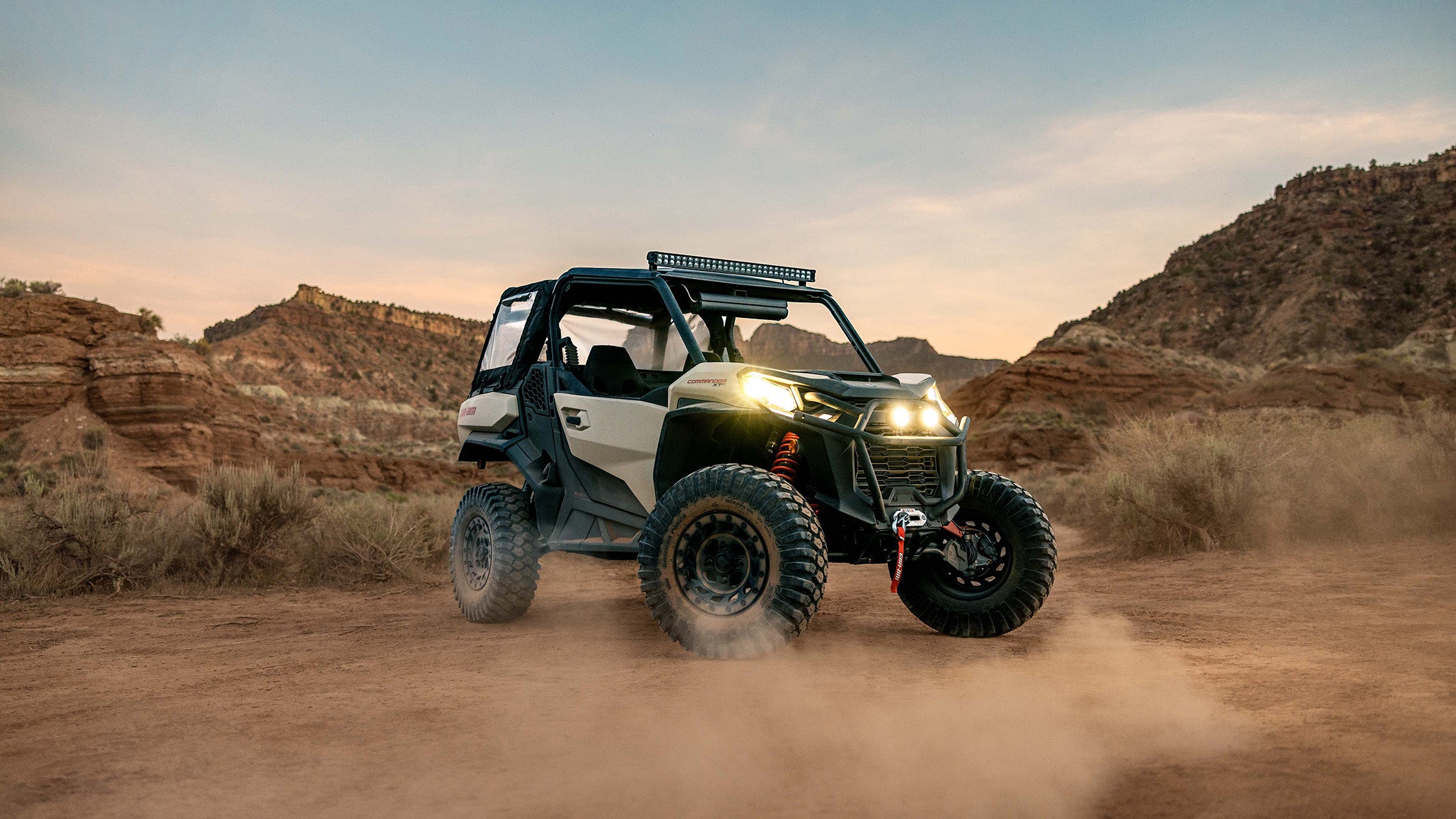 Can-Am Commander (side-by-side) equipped with a PERFEX Industries lift kit, powerfully navigating the desert terrain, showcasing the vehicle's enhanced off-road capabilities and ruggedness.