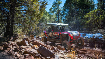 Honda Talon (side-by-side) with a PERFEX Industries lift kit, actively traversing an off-road trail, demonstrating its enhanced capability and adventurous spirit in rugged terrain.