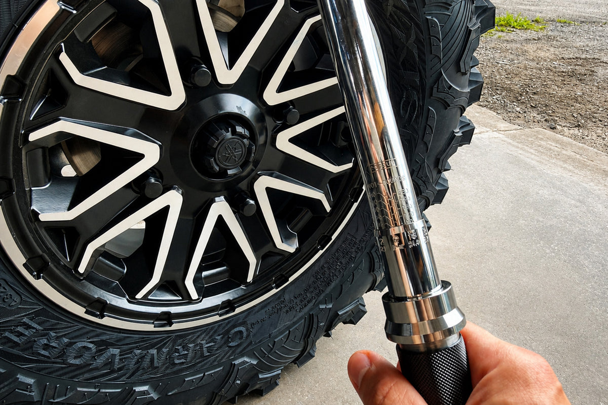 Final torquing of ATV or UTV wheel lug nuts in a star pattern using a torque wrench after wheel spacer installation.
