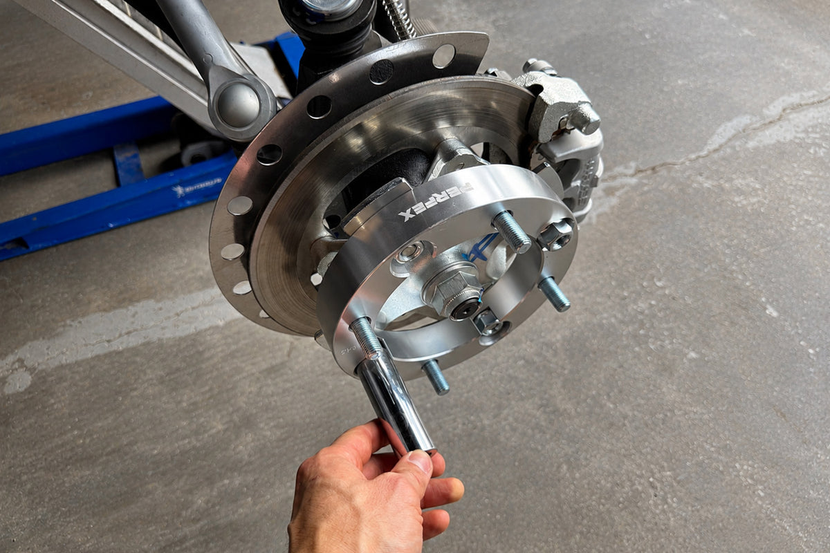 Installing a wheel spacer on an ATV or UTV by hand-tightening it onto the factory wheel studs before final torque.