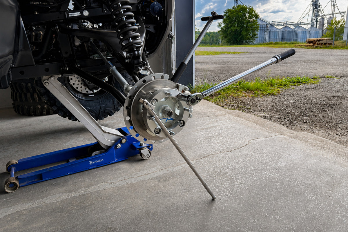 Torquing ATV or UTV wheel spacer nuts in a star pattern with a torque wrench while holding the hub with a breaker bar to prevent rotation.