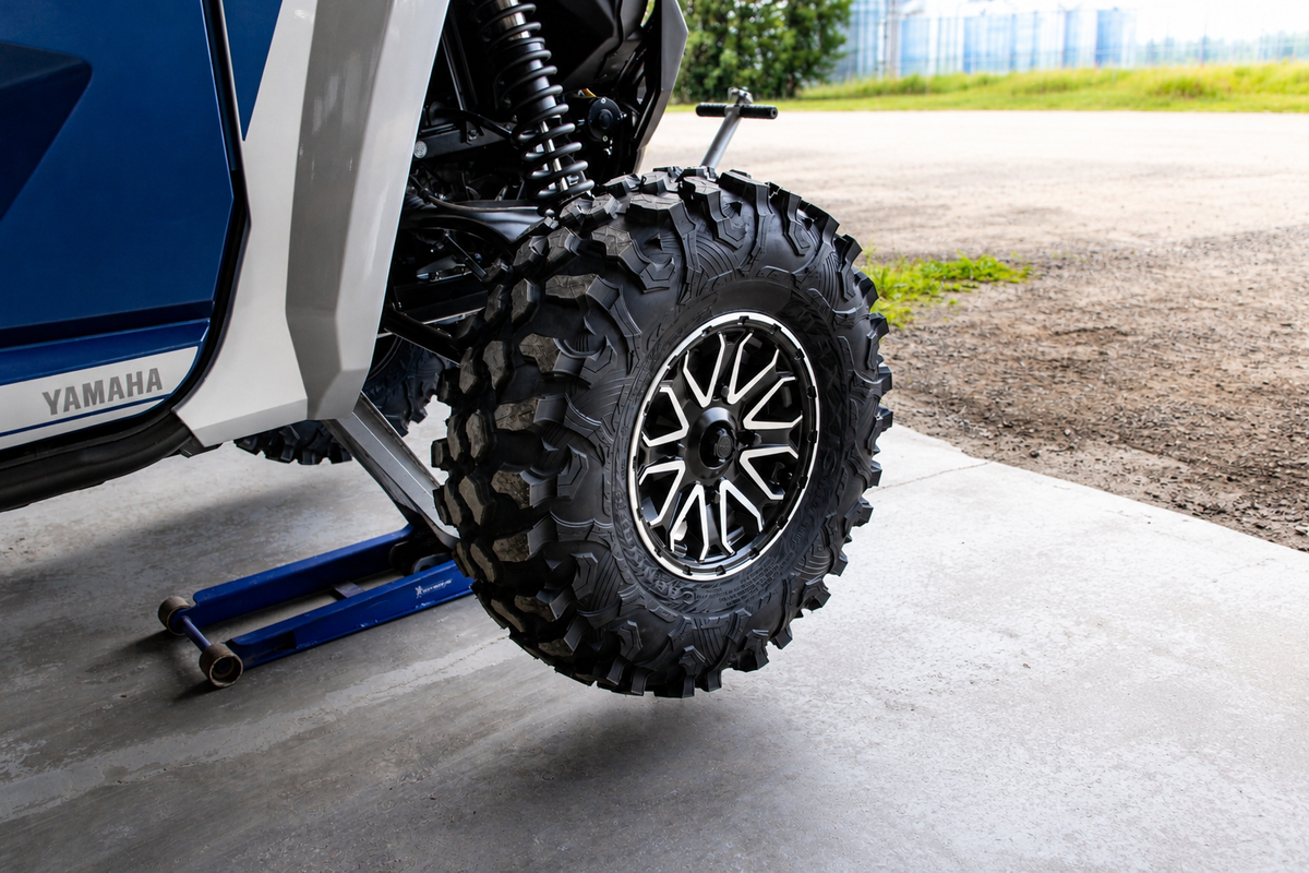 Lifting an ATV or UTV with a floor jack before installing wheel spacers, with the tire raised just off the ground.