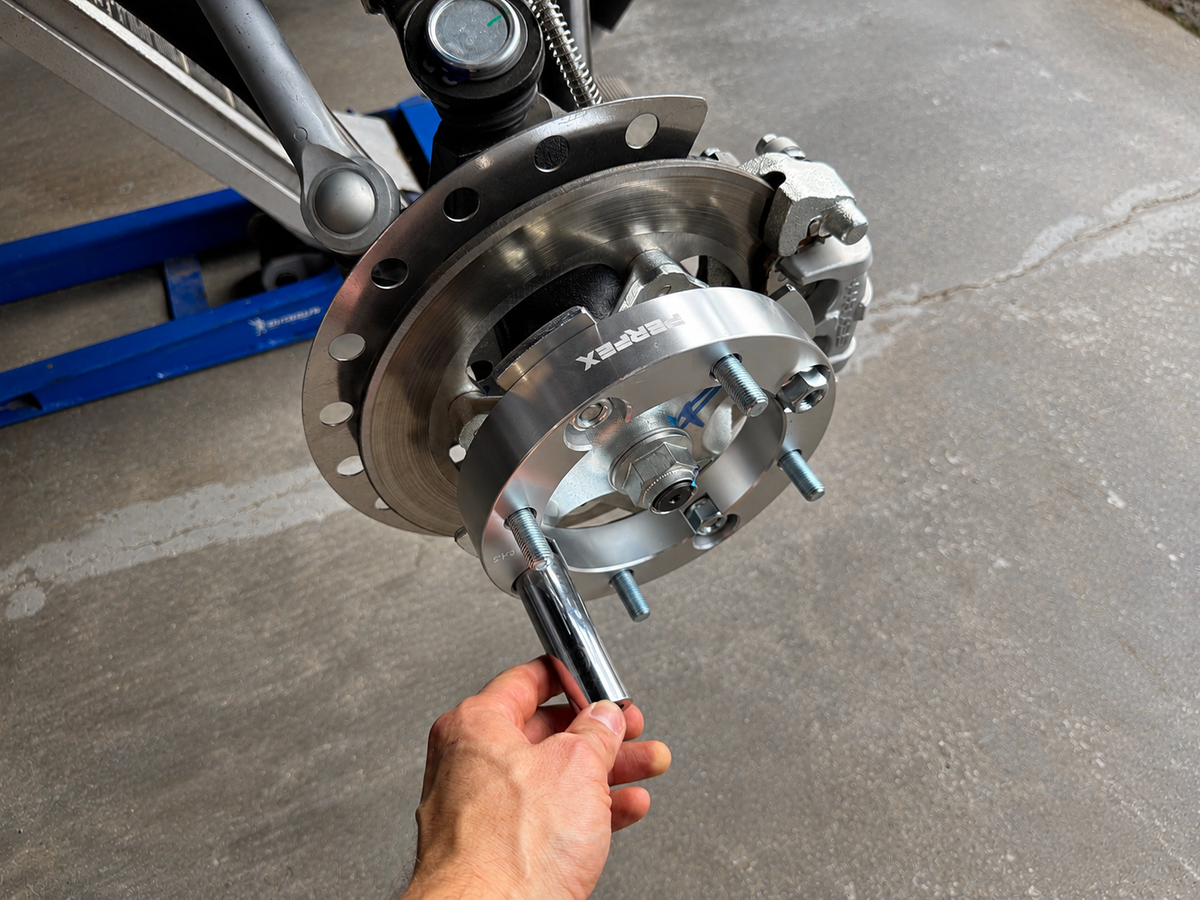 Installing a wheel spacer on an ATV or UTV by hand-tightening it onto the factory wheel studs before final torque.